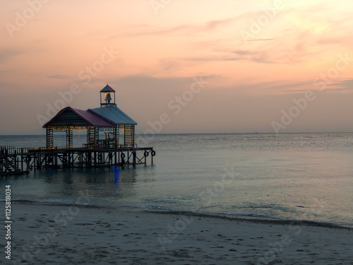 Serene Sunset Pier with Illuminated Pavilion Over Calm Ocean Waters on Sandy Beach at Pulau Lang Tengah, Malaysia