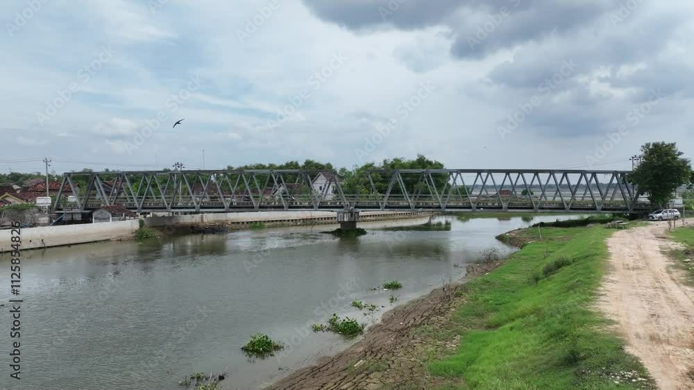 Drone video of two spans steel truss bridge type b50 over a river surrounded by rice fields in Sampang, Central Java Indonesia Drone video of two spans steel truss bridge type b50 over a river surrounded by rice fields in Sampang, Central Java Indonesia