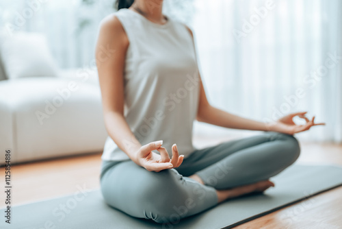 Fotografía Young Asian woman meditating in lotus position at home, sitting on the floor in fitness clothing