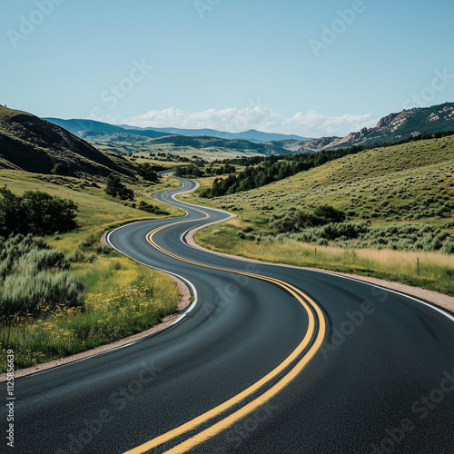 A winding asphalt road curves through a tranquil landscape on a clear day, inviting travelers to explore the journey ahead.