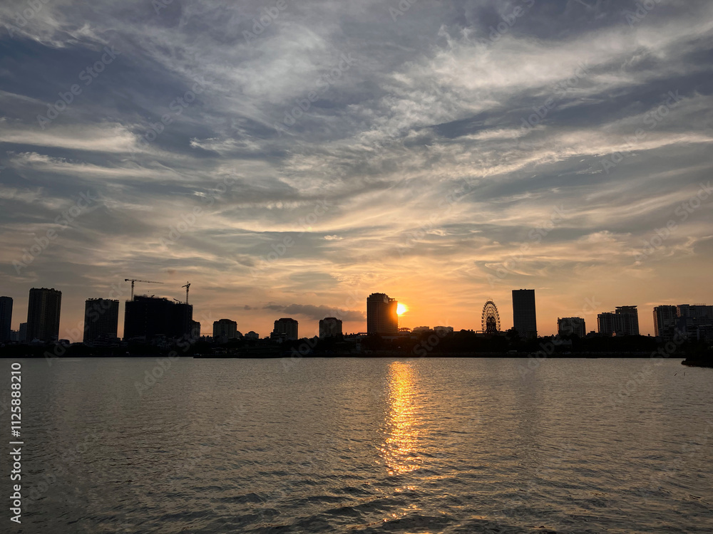 Fototapeta premium City Sunset Silhouette: Urban Skyline Reflected Over Calm Waters at Dusk in Hanoi, Vietnam