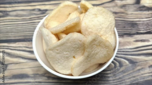 A pile of shrimp crackers in a small bowl. Shrimp crackers are made from a mixture of tapioca flour and finely pounded shrimp with spices and flavor enhancers. A snack from Sidoarjo, Indonesia. photo