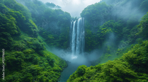 Nature background showcasing a misty waterfall surrounded by lush green foliage