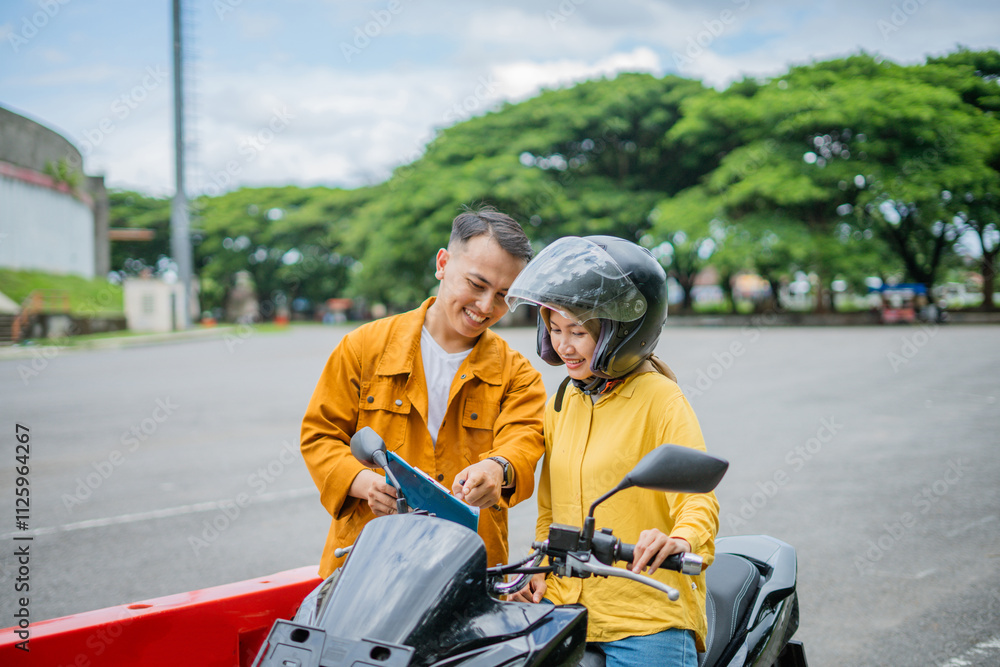 a trainer is showing a board to a motorcyclist