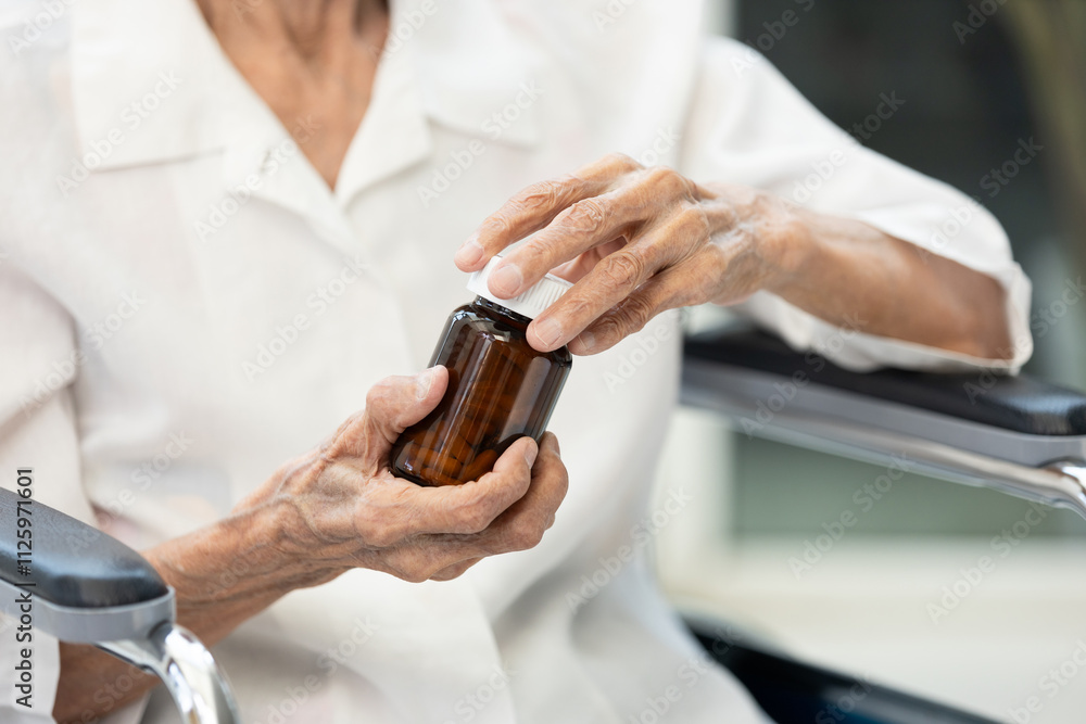 Hands of elderly holding bottle of medication,senior sitting in wheelchair,taking capsules,pills tablets,vitamin or supplement,health care,treatment or prevention of disease,medical,medicine concept Hands of elderly holding bottle of medication,senior sitting in wheelchair,taking capsules,pills tablets,vitamin or supplement,health care,treatment or prevention of disease,medical,medicine concept
