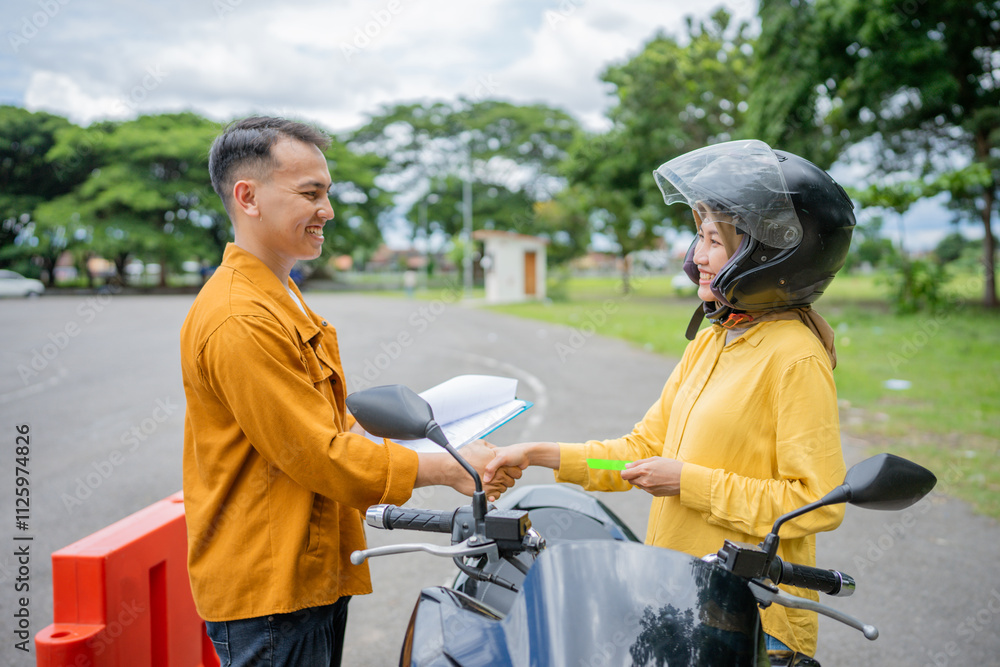 a male instructor and a female motorcyclist shake hands a male instructor and a female motorcyclist shake hands