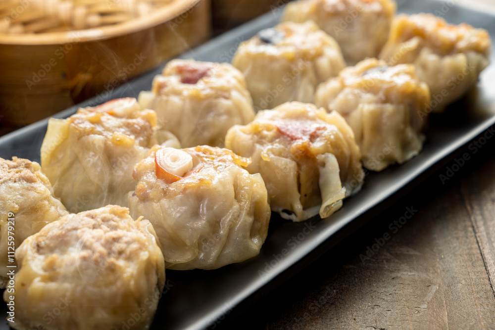 Assorted chinese dim sum dumpling on the plate with bamboo wooden basket bowl on wooden table
