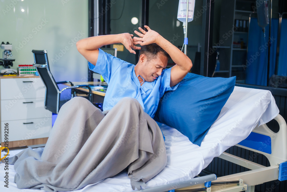 Obraz premium A man with depression sits alone on a hospital bed, feeling stressed, anxious, and bored. He experiences phobia symptoms, including fear, rapid heartbeat, dizziness, sweating, and severe anxiety