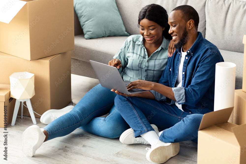 Happy Young African Spouses Using Laptop After Moving To New Home, Smiling Black Couple Choosing Furniture Online, Sitting With Computer On Floor Among Cardboard Boxes With Belongings, Closeup Happy Young African Spouses Using Laptop After Moving To New Home, Smiling Black Couple Choosing Furniture Online, Sitting With Computer On Floor Among Cardboard Boxes With Belongings, Closeup