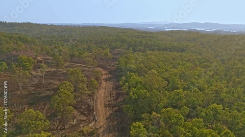 A recently graded dirt road cuts through the thick vegetatation of the Australian bush
