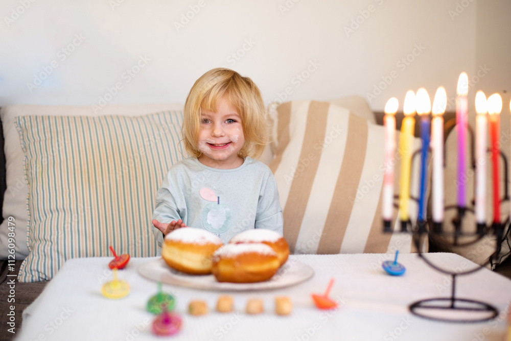 Child smile and happy. on table donuts and traditional menorah with lighting candles and Savion. holiday in Israel Child smile and happy. on table donuts and traditional menorah with lighting candles and Savion. holiday in Israel