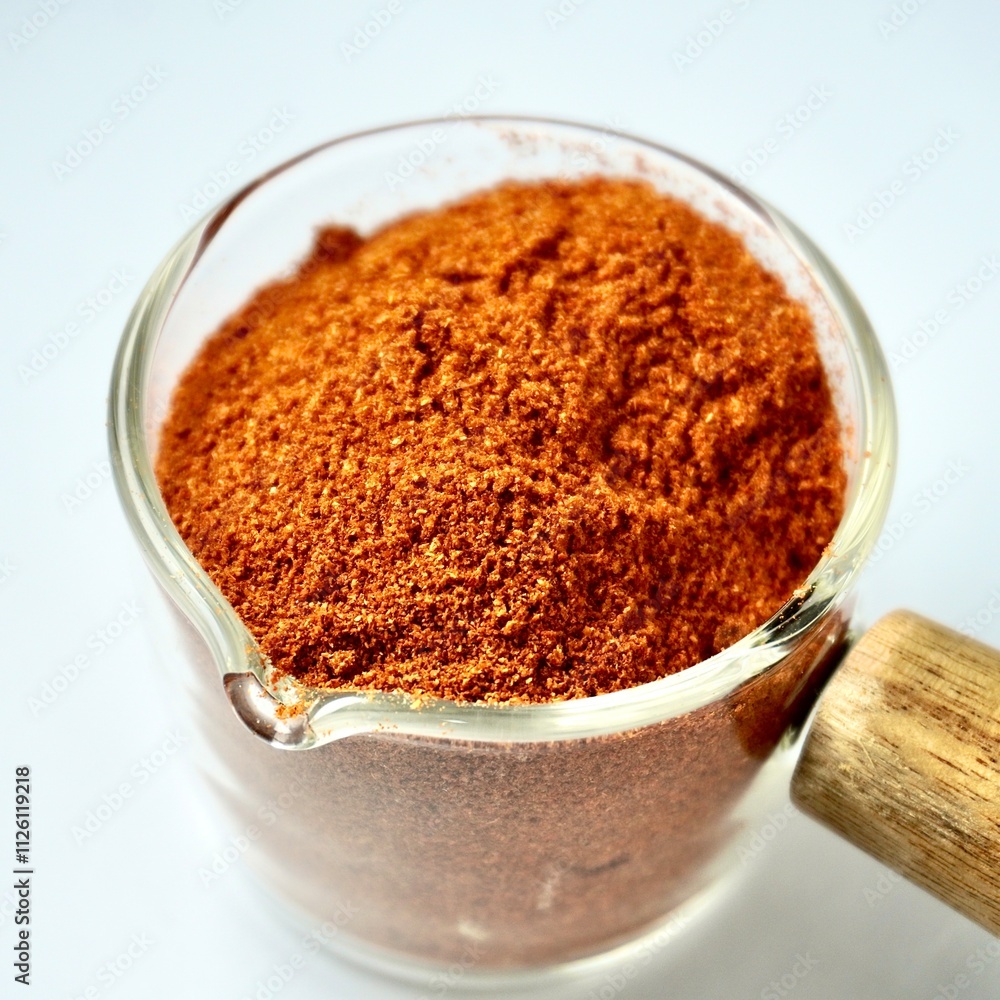 Red paprika powder food ingredients in glassware pot cup isolated on square white background. Red paprika powder food ingredients in glassware pot cup isolated on square white background.