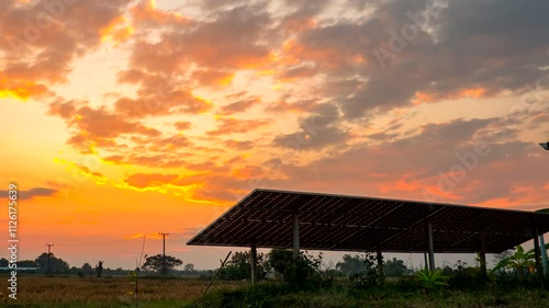Time-lapse sun setting in front of silhouette Solar Cells panel, The Video has dolly zoom-out.
