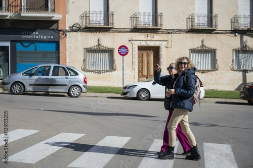 Wallpaper Mural Two women over 50 crossing a street in a rural Spanish town, enjoying their walk and exploring the local surroundings on a sunny day Torontodigital.ca