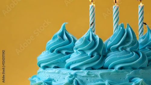 Whipped blue frosting with striped candles against a yellow background.