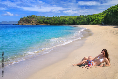 Young woman with a baby girl sitting at Anse La Roche Beach, Carriacou Island, Grenada. photo