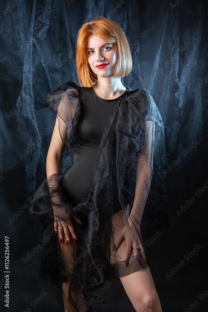 A young red-haired girl in a black bodysuit poses in the studio against a dark background.