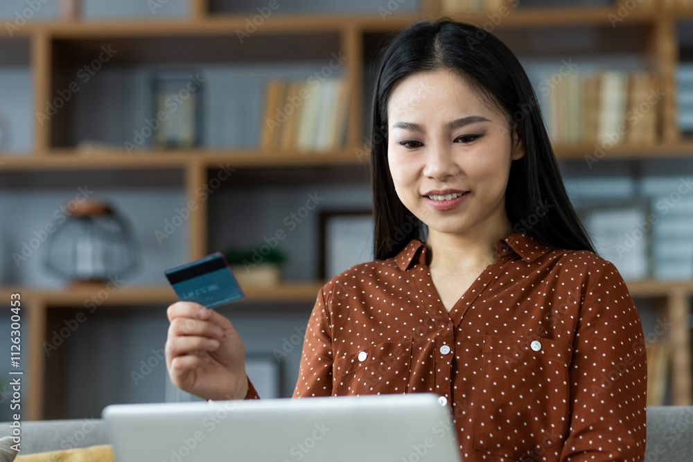 Smiling woman holds credit card while shopping online with laptop, enjoying convenience of e-commerce. Comfortable home setting reflects relaxed atmosphere and modern lifestyle. Smiling woman holds credit card while shopping online with laptop, enjoying convenience of e-commerce. Comfortable home setting reflects relaxed atmosphere and modern lifestyle.