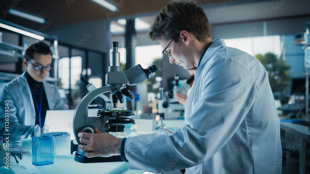 Portrait of a Handsome Caucasian Student Working on a Research Project in University. Medical Research Scientist Looking at Biological Samples Under a Microscope in an Applied Science Laboratory Portrait of a Handsome Caucasian Student Working on a Research Project in University. Medical Research Scientist Looking at Biological Samples Under a Microscope in an Applied Science Laboratory