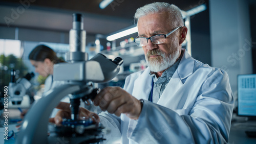 Senior Medical Research Scientist Looking at Biological Samples Under a Microscope in an Applied Science Laboratory. Portrait of a Handsome Middle Aged Doctor Working on a Research Project