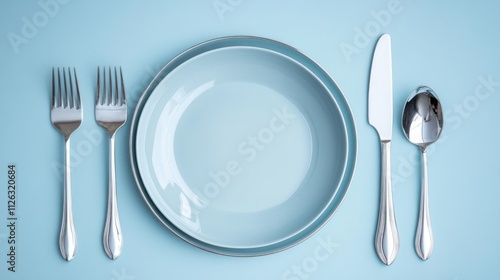 Elegant place setting with light blue plates and silverware on a pastel blue background.