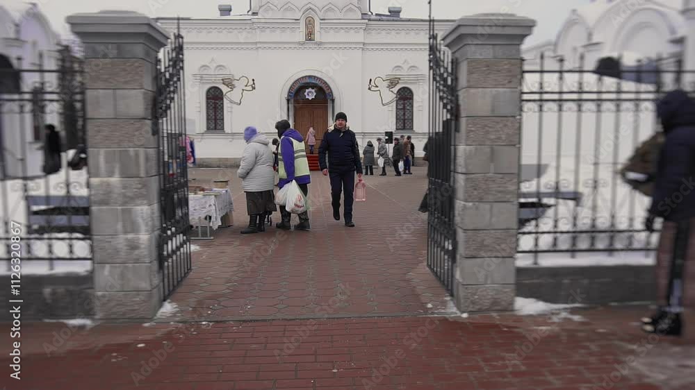 Orthodox Christian carries plastic bottle of consecrated sanctified water in his hand. Believer leaves temple grounds. Man came to church for holy water. Feast of Baptism of Jesus in winter. Epiphany
