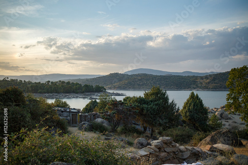 Scenic overlook of a reservoir, with hills, trees, and a small structure.  Tranquil landscape at sunset. photo