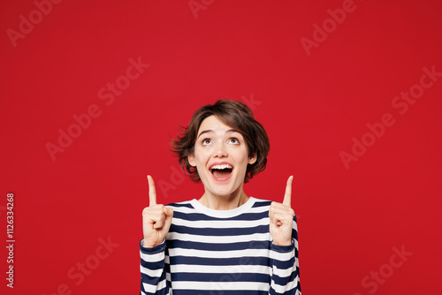 Young surprised shocked happy woman she wear blue striped sweatshirt casual clothes point index finger overhead on empty area mockup isolated on plain red background studio portrait Lifestyle concept