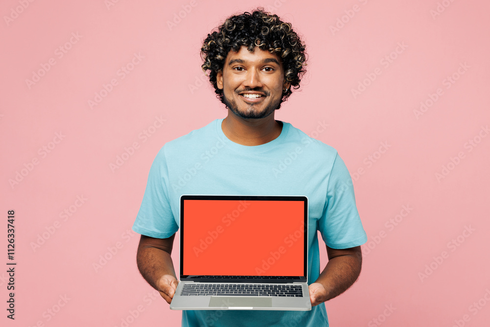 Young IT Indian man he wear blue t-shirt casual clothes hold use work on laptop pc computer with blank screen workspace area isolated on plain pastel light pink background studio. Lifestyle concept.