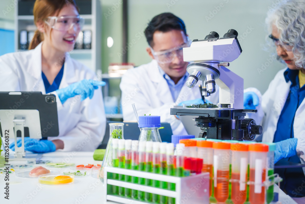 A male scientist and two women conduct plant research in a laboratory. microscopes, petri dishes,test tubes to analyze genetically modified plants, food, meat, eggs,vegetables for nutritional value A male scientist and two women conduct plant research in a laboratory. microscopes, petri dishes,test tubes to analyze genetically modified plants, food, meat, eggs,vegetables for nutritional value