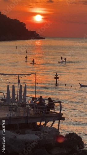 a group of people eating others paddleboarding at sunset on the amalfi coast