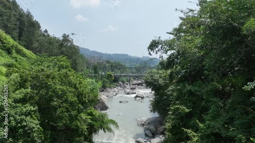 Video of B60 type steel truss bridge replacing the old collapsed bridge next to it over a clear river with incredibly beautiful natural scenery photo