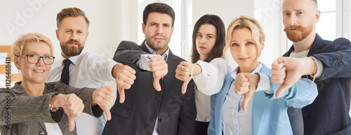 Business people team looks at camera showing thumbs down, dissatisfied face expression, dislike negative disagreement, disapproval, rejection, negative emotion, unsuccessful businessmen meeting