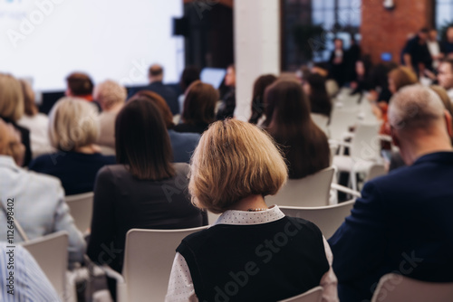 Female audience at the symposyum meeting, participants attendees in conference room hall listens to lecturer, group of women on a congress together listen to speaker on a stage at master-class