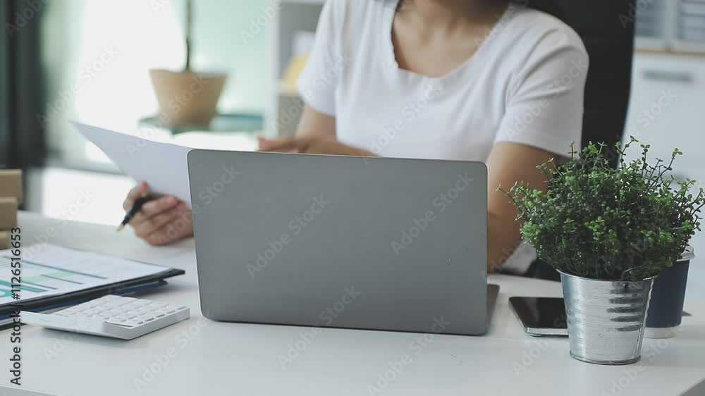 Asian Businesswoman Using laptop computer and working at office with calculator document on desk, doing planning analyzing the financial report, business plan investment, finance analysis concept. Asian Businesswoman Using laptop computer and working at office with calculator document on desk, doing planning analyzing the financial report, business plan investment, finance analysis concept.
