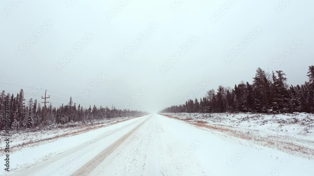 Car driving down an empty snow-covered highway during a daytime blizzard Car driving down an empty snow-covered highway during a daytime blizzard