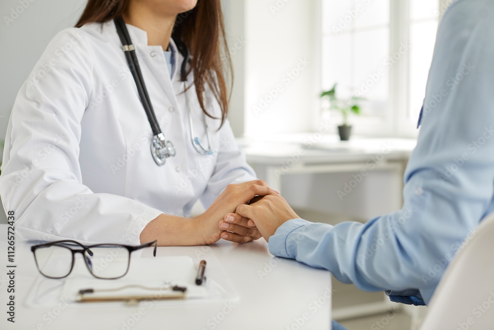 A female doctor calms a patient and holds his hand, close-up. Concept of medical trust and participation. Consultation and diagnosis in the clinic, medical assistance, friendly hospital staff