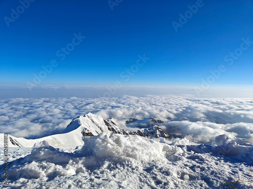 Wallpaper Mural Stunning view from a high altitude showing snow-covered peaks and clouds beneath a bright blue sky Torontodigital.ca