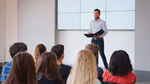 Bild auf Leinwand Male Teacher Giving Presentation To High School Or University Class In Front Of