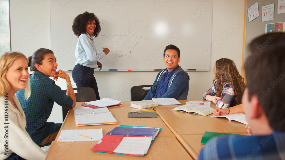 Female Tutor At Whiteboard Teaching Class Of High School College Or University Students Around Table Female Tutor At Whiteboard Teaching Class Of High School College Or University Students Around Table