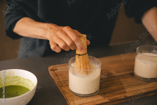 Wallpaper Mural Woman at home in kitchen make matcha tea latte with oats milk, shake milk with bamboo whisk. Torontodigital.ca