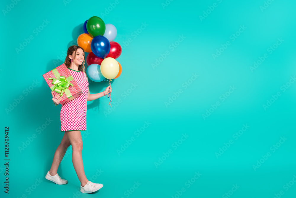 Fototapeta premium Full length photo of lovely teen lady walk hold gift air balloons dressed stylish pink plaid garment isolated on cyan color background