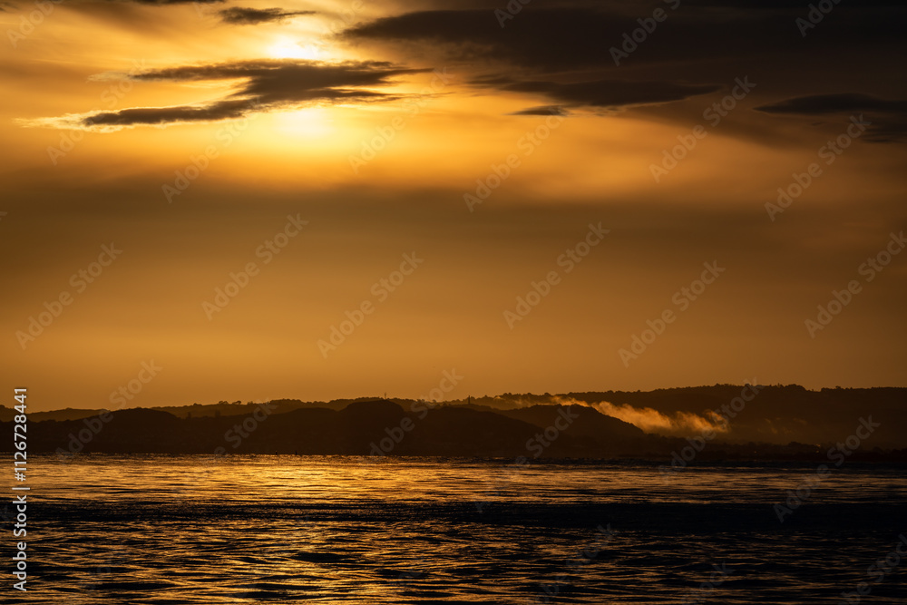 Naklejka premium Sunrise over sea and distant land