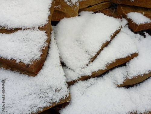 Flat brown sandstone stones under a layer of white cold snow. Background of stones and sediment. photo