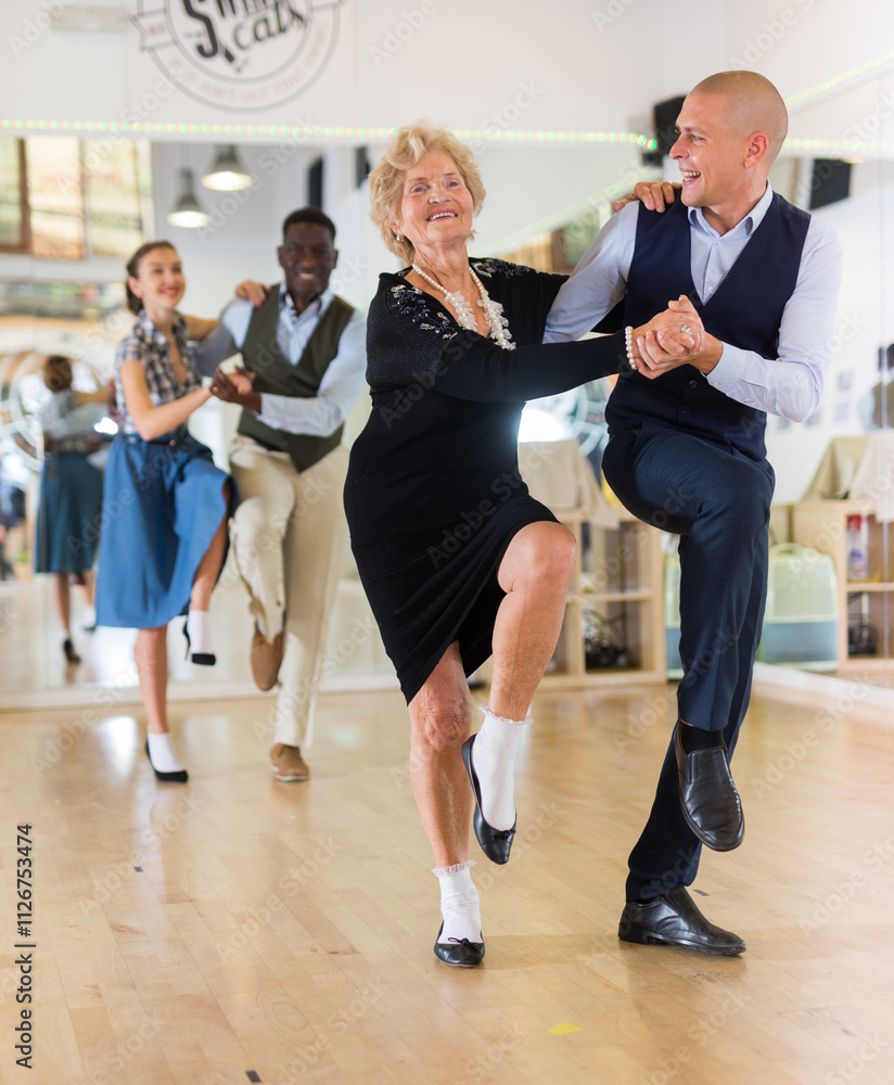 Fototapeta premium Senior woman and younger man dancing swing in studio