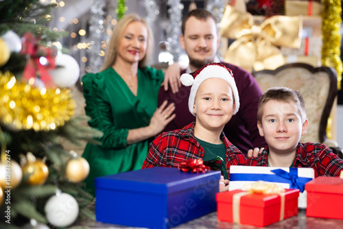 Children and parents give each other gift boxes during Christmas or New Year celebrations at home