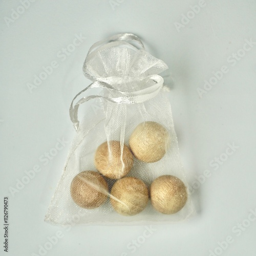 Anti smell odor and insect wooden balls for replacing camphor in white transparent pouch bag isolated on square white background from above angle view. photo