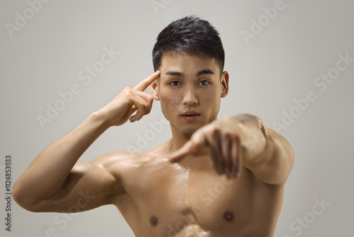 Shirtless muscular Asian man pointing to his head and forward, symbolizing focus, determination, and mental strength. Perfect for motivational, fitness, and personal growth campaigns.  photo