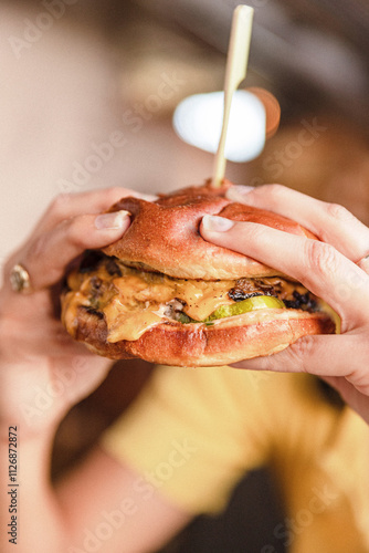 Person Holding Cheeseburger in a Restaurant
