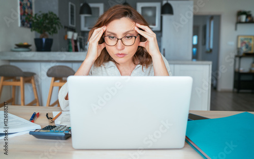 Beautiful middle-aged pensive woman in glasses with monthly bills thinking about family home budget. Small business, home finances, money savings concept image.